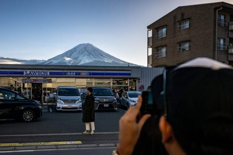 سائح يقف أمام متجر صغير ويظهر جبل فوجي في الخلفية