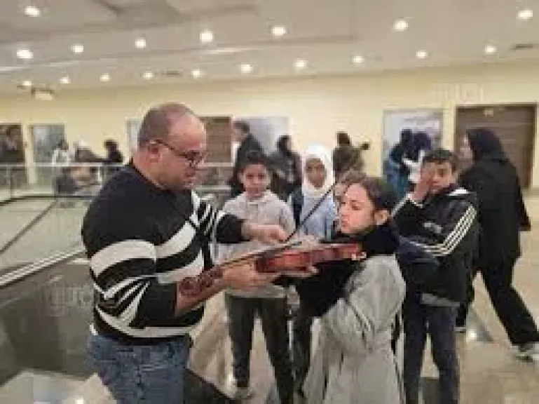 مشهد استثنائي، شاب يعلم أطفال معرض الكتاب فنون العزف على الكمان مجانا